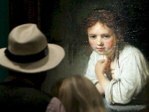 Un cuplu priveste la pictura "Tanara fata aplecata la fereastra" (1645), lucrare a faimosului pictor olandez Rembrandt, expusa in cadrul unei expozitii cu titlul "Rembrandt. Cautarea unui geniu", la Galeriile Gemaelde, 03 August 2006 in Germania la Berlin. (OLIVER LANG / AFP / Getty Images)