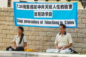 Dna Ng Chye Huay (stanga) si dnul Erh Boon Tiong au desfasurat un protest peste drum de ambasada chineza din Singapore la 20 iulie. Autoritatile singaporeze l-au internat fortat pe avocatul Madasamy Ravi, care ii apara pe practicantii Falun Gong, intr-un spital psihiatric. (The Epoch Times)