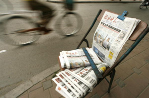 Beijing, China: Ciclistii trec pe langa vanzatorii de ziare de pe o strada din Beijing. Departamentul de Propaganda al Partidului Comunist Chinez a anuntat planuri pentru a intari si mai mult controlul asupra mass mediei printate, prin introducerea unui sistem de punctare. 