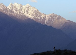 Soarele apune in muntii Himalaya in timp ce un paznic supravegheaza locul. 