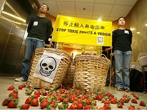 Activistii Greenpeace stau in fata unor fructe contaminate in timpul unui protest in Hong Kong. 