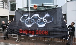 Grupul Reporteri Fara Frontiere afiseaza un steag mare cu inelele Olimpice transformate in catuse. 