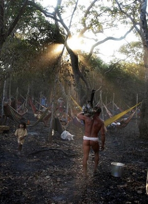 Un indian brazilian Ywalapiti cara lemne pentru a face foc in timp ce fotografii privesc. 