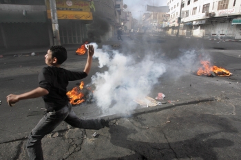 Un tinar palestinian arunca cu o grenada de gaze lacrimogene catre soldatii israelieni in orasul Hebron din West Bank, 5 decembrie 2008 in timpul unui protest impotriva violentelor cauzate de colonistii evrei. Fortele de securitate se asteapta la mai multe violente dupa ce aripa dura israeliana a inceput ciocniri violente impotriva palestinienilor 
