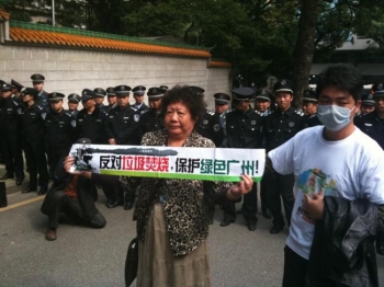 O femeie protesteaza in districtul Panyu din Provincia Guangzhou. Mesajul pe care il afiseaza inseamna: "Ne opunem incineratorului de gunoi, pastrati verde Guangzhou!" 
