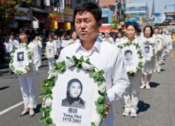 Participantii la o parada din Flushing, New York, afiseaza portrete cu practicanti Falun Gong ucisi in China. Barbatul din prim plan prezinta portretul lui Yang Mei, care a fost ucisa in 2001 pentru credinta ei in Falun Gong, intr-un lagar de munca fortata din China. 