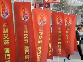 Un barbat trece pe langa bannere campaniei de oprire a HIV/SIDA in Beijing. China are deja o problema cu SIDA, si aparent, acum mai are una cu o boala asemanatoare SIDA, insa neidentificata. 