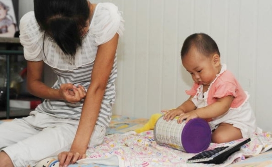 In varsta de 13 luni, fetita Xiaoying se joaca langa mama sa in Beijing, 9 august 2010, dupa ce a fost diagnosticata cu crestere prematura a sanilor (STR / AFP / Getty Images)