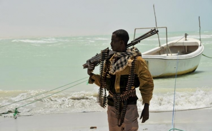 Somalez, facand parte atat din clanurile de pirati cat si din grupurile islamice radicale, purtand o arma de calibru mare pe plaja din Hobyo, august 2010 (Roberto Schmidt / AFP / Getty Images)