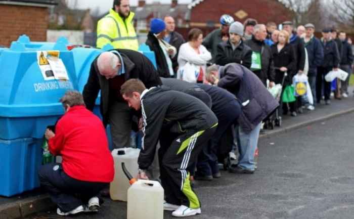 Irlandezi stand la coada cu sticle si containere la Avoniel Leisure Centre in Belfast, 29 decembrie 2010. 