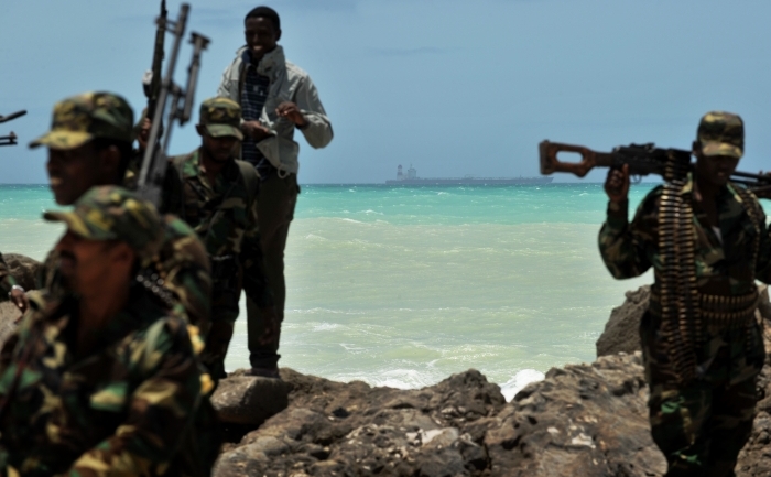 Insurgenti somalezi impreuna cu pirati in orasul Hobyo. Pe fundal se poate observa un tanc petrolier coreean capturat, 20 august 2010 (ROBERTO SCHMIDT / AFP / Getty Images)