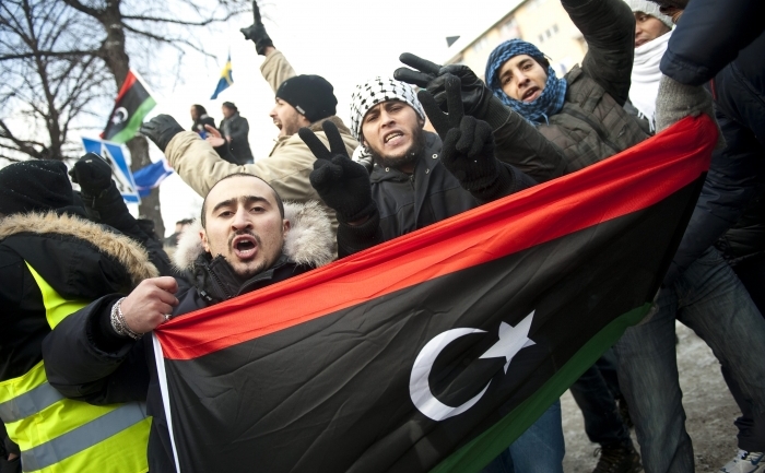 Manifestanţi libieni arantand vechiul steag libian în timpul unui protest împotriva liderului libian Moamer Gadaffi în faţa ambasadei din Stockholm pe 22 februarie 2011
