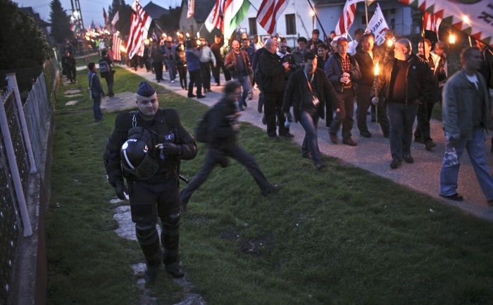 Un politist ungar (ST) escorteaza membri si simpatizanti ai partidului ultranaţionalist Jobbik care demonstreaza impotriva crimei din Hejoszalonta, nord-estul Ungariei, 2 aprilie 2011. Consiliul local din Tiszavasvari, oraş din estul Ungariei controlat de partidul ultranaţionalist Jobbik, şi-a lansat propria jandarmerie săptămîna aceasta, pentru că poliţia nu a reuşit să împiedice "crimele romilor".