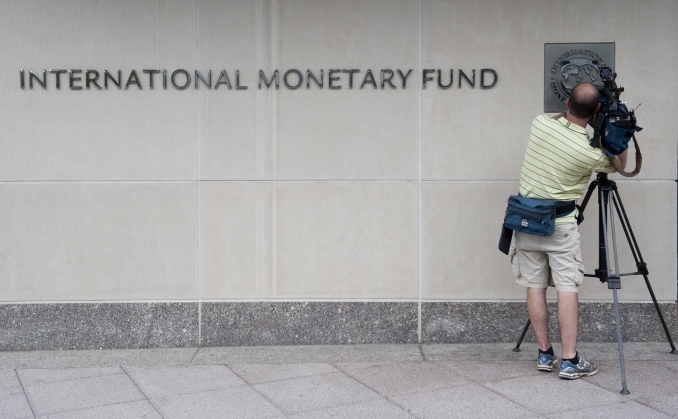 Un cameraman filmeaza logo-ul Fondului Monetar International, la sediul organizaţiei din  Washington, DC.