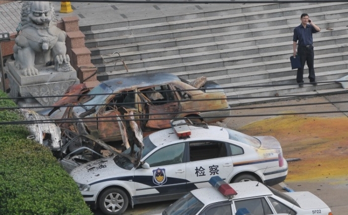 Un oficial stand lângă autovehicule avariate langa un birou al guvernului, in urma unei explozii, în oraşul Fuzhou din estul Chinei, pe 26 mai
