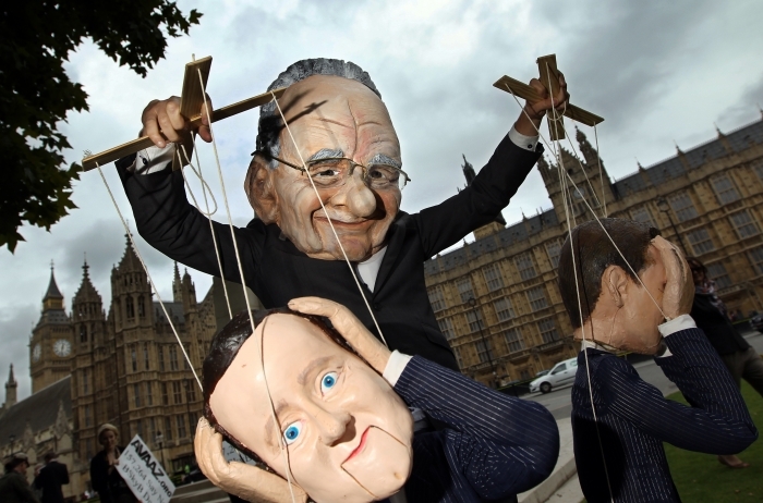 Un papusar imbracat in Robert Murdoch se joaca cu papusile lui David Cameron si cea a ministrului britanic al culturii, mass-mediei si sportului, Jeremy Hunt, in timpul protestelor.