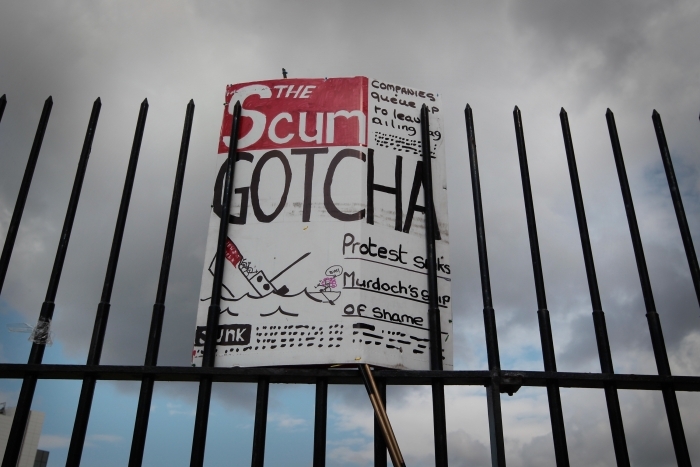 O parodie a primei pagini a ziarului The Sun, fratele lui News of The  World, cu inscriptia "Te-am prins!", care atarna pe un gard din  apropierea sediului News International, pe 9 iulie 2011.