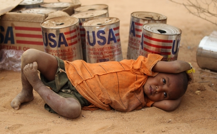 Copil odihnindu-se langa niste cutii provenind din ajutoarele americane, in tabara de refugiati Dagahaley, parte a lagarului Dadaab, 19 iulie 2011 in Dadaab, Kenya. Lagarul de refugiati este situat la granita dintre Kenya si Somalia si adaposteste 400 de mii de persoane, de patru ori mai mult decat incarcarea maxima. (Oli Scarff / Getty Images)