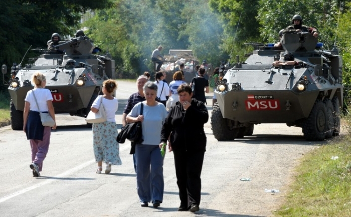 Kosovo: femei trec pe langa forţele austriace NATO din Kosovo (KFOR), pe un drum din apropierea satului Rudare, pe 3 august 2011.