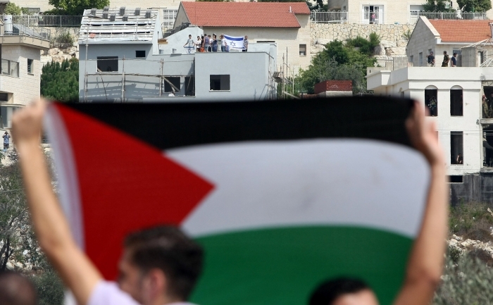 Protestatari palestinieni flutura un steag national palestinian.