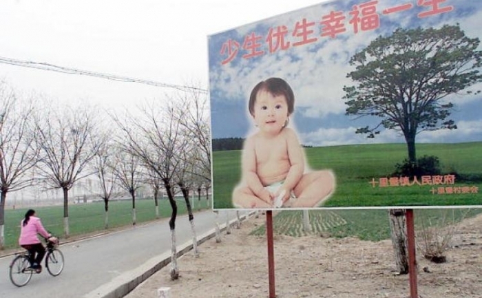 <p>O femeie trece pe langa un panou care încurajeaza cuplurile de a avea un singur copil, într-o suburbie din Beijing, 25 martie 2001.</p> (Goh Chai Hin / AFP / Getty Images)