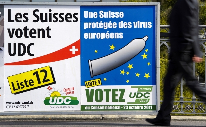 Un barbat trece pe langa un poster de campanie al Partidului Poporului elveţian, de extremă-dreaptă, care pare să fie pe placul populaţiei, prin campania sa agresivă ce susţine că "imigraţia în masă" ia slujbe de la elveţieni.