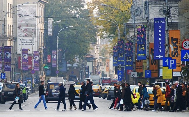 Oamenii trec strada la o trecere de pietoni din Piata Victoriei, Bucuresti.