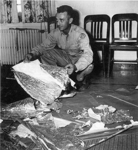 Maiorul Jesse Marcel aparţinând de Roswell Army Air Field cu rămăşiţe la 140 km  nord-vest de Roswell, NM, in iunie 1947. Rămăşiţele au fost identificate ca aparţinând unei ţinte radar