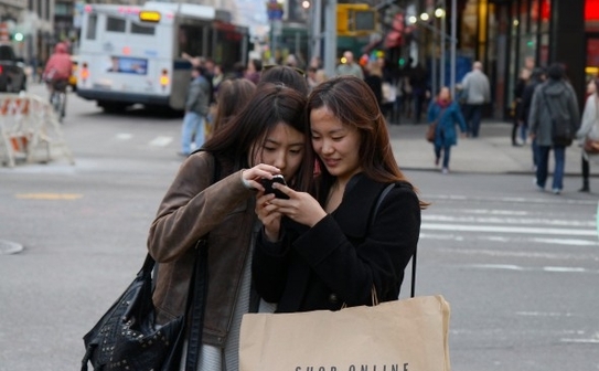 Două femei se uite la un smartphone in Districtul Flatiron din Manhattan duminică. (Benjamin Chasteen / The Epoch Times)