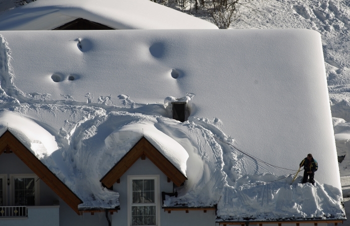 Un locuitor înlătură zăpada de pe acoperişul unui hotel din Ischgl, Austria, 11 ianuarie. În ultima săptămână ninsorile abundente au provocat haos în unele regiuni din Austria şi Elveţia, prin blocarea conexiunilor feroviare şi rutiere, creând riscul de avalanşe.