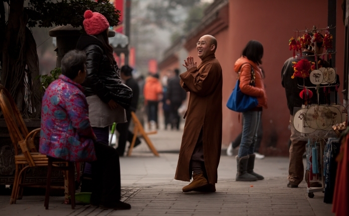 Un călugăr tibetan salută trecătorii pe o stradă din Chengdu, capitala provinciei Sichuan, ianuarie 2012. Comunităţi importante de etnici tibetani trăiesc în mai multe zone din provincia Sichuan, aflată la graniţa cu Tibetul.