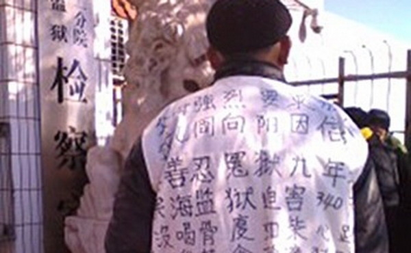 Tatăl lui Zhou Xiangyang purtănd un tricou înscris prin care denunţă persecutarea fiului său Zhou Xiangyang, şi cere eliberarea lui.