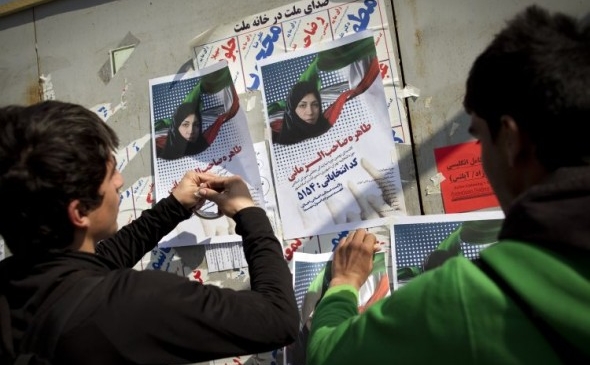 Iranieni pun posterele unui candidat pentru alegerile parlamentare în centrul oraşului Teheran pe 28 februarie. (Behrouz Mehri / AFP / Getty Images)