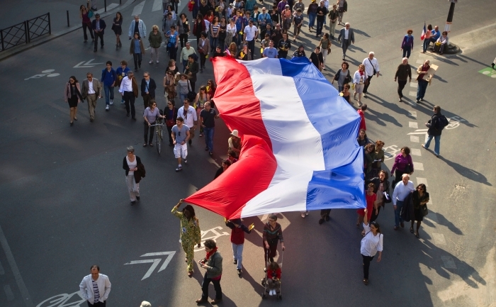 Oameni flutură un steag gigant pe 25 martie 2012, într-un marş din Paris pentru recentele crime din Toulouse.