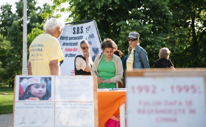 Trecători din parcul Crângaşi sunt informaţi de către voluntari despre practica Falun Dafa şi despre persecuţia acesteia în China, 13 mai 2012.