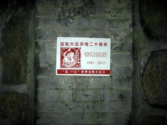 Un afiş pe care scrie: "Sărbătorind a 20-a aniversare a Falun Dafa în lume", lipit pe un perete al Universităţii Beijing.
