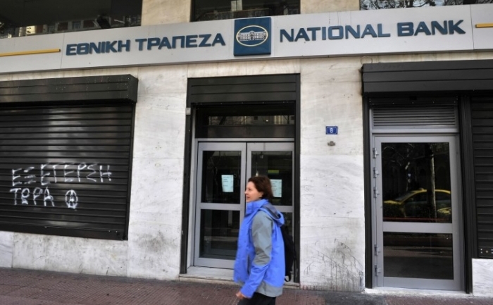 O femeie trece prin faţa unei sucursale a Bancii Naţionale a Greciei anul trecut. (Louisa Gouliamaki / AFP / Getty Images)