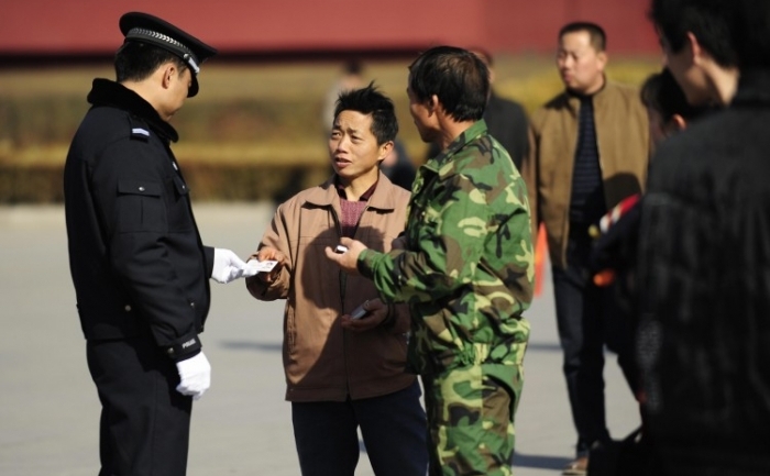 Un poliţist verifică un card de identitate al unui turist, Piaţa Tiananmen din Beijing, pe 1 martie 2009.