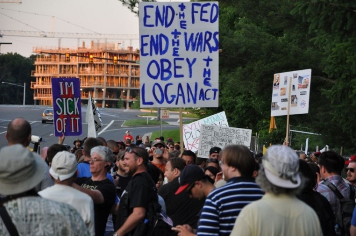 Protestatar împotriva Grupului Bilderberg - cu o pancardă pe care scrie "Terminaţi Federal Reserve, opriţi războaiele, respectaţi Legea Logan", Chantilly, 2 iunie