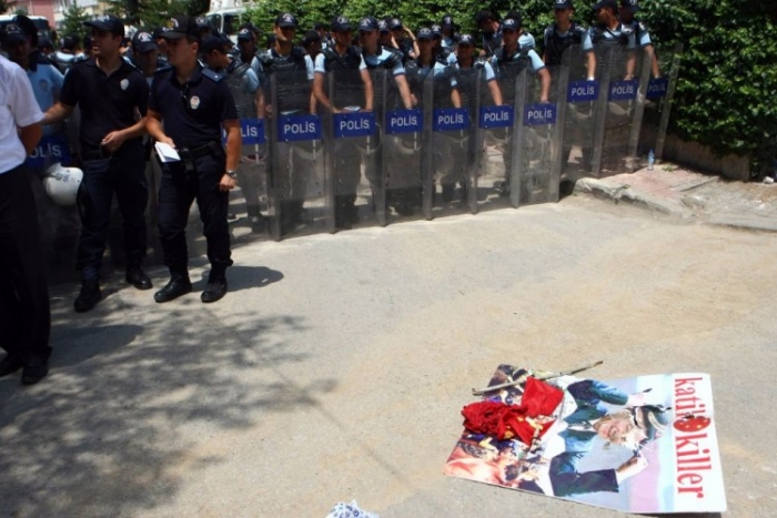 Ofiţeri de poliţie stau lângă un steag chinez ars şi un poster al liderului comunist Hu Jintao, în faţa ambasadei Chinei din Turcia