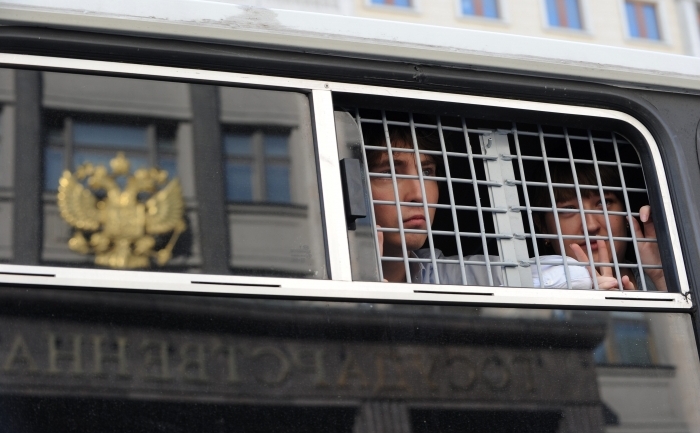 Un protestatar rus deţiunut priveşte printr-o fereastră a dubei de poliţie în care este reflectată Duma Rusiei, mai 2012