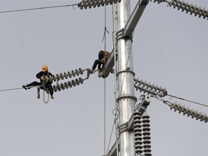 Lucrătorii chinezi de pe turnul de înaltă tensiune repară cablurile din provincia Anhui dn estul Chinei pe 18 martie. 