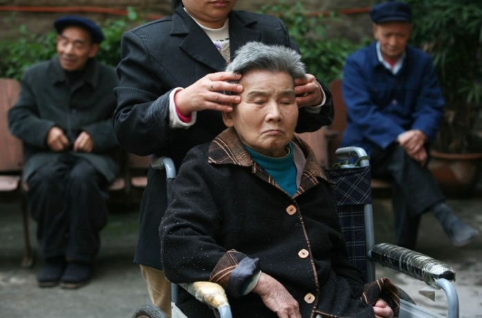 Un însoţitor îi face masaj pentru unui cetăţean senior într-un centru de îngrijire al bătrânilor pe 16 octombrie 2007 în Chongqing, China.