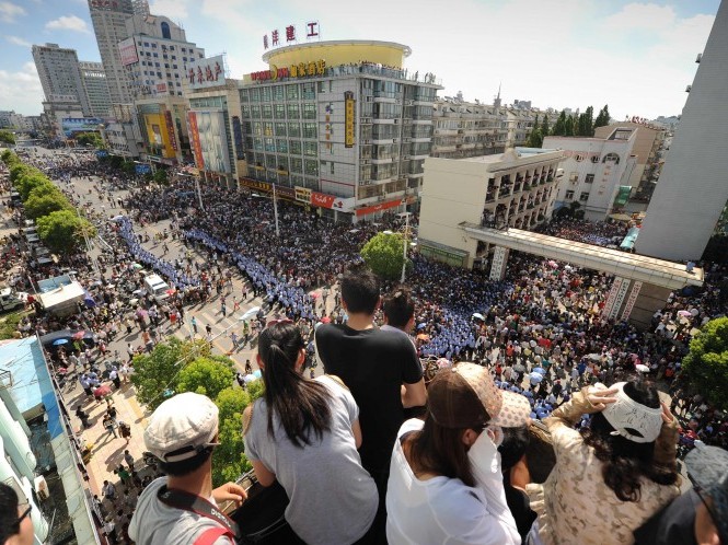 Localnicii se uită la proteste în Qidong, un oraş din aproapierea oraşului Shanghai, de pe un acoperiş din apropiere, pe 28 iulie. Activiştii au îndemnat la proteste în Shanghai, iar poliţia face arestări şi pune oameni sub supraveghere.