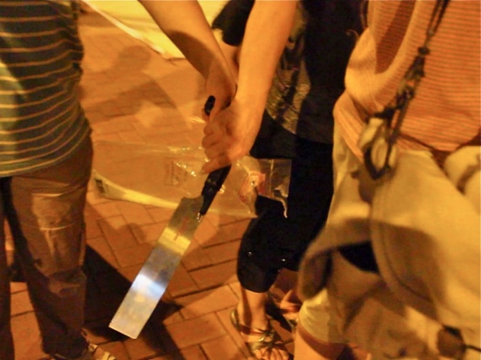 O persoană afiliată cu Asociaţia de Sprijin pentru Tineret din Hong Kong ţine în mână un cuţit, într-un incident ăn care grupul a ameninţat aderenţii Falun Gong (The Epoch Times)