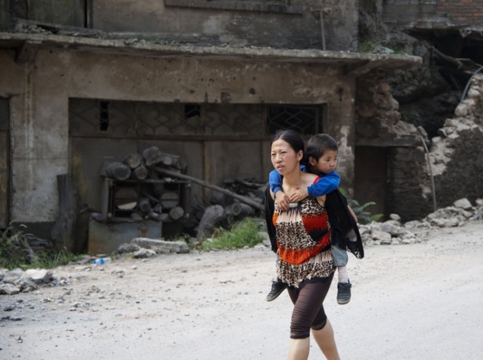 Femeie cu un copil în spate pe străzile din Yiliang, la două zile după cutremurul de la începutul lunii septembrie 2012