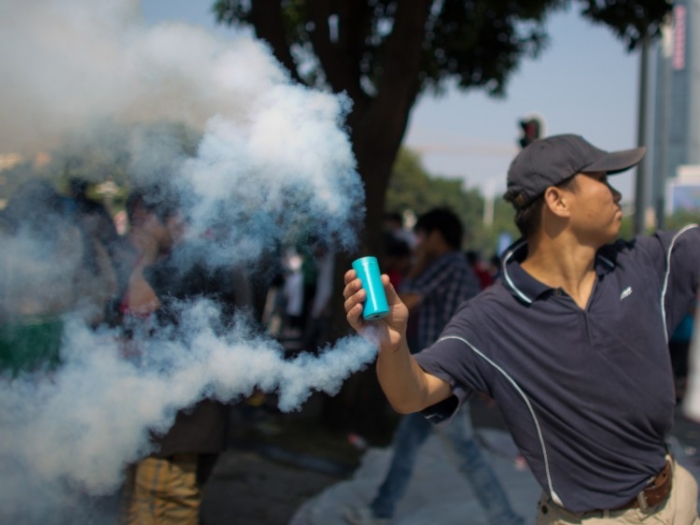 Un protestatar anti-japonez aruncă cu gaz în timpul demonstraţiei pentru Insulele Diaoyu, 16 septembrie, în Shenzhen, China. Unii analişti suspectează că o facţiune a regimului comunist chinez poate fi în spatele acţiunii. (Lam Yik Fei / Getty Images)
