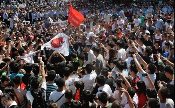 Demonstranţi chinezi ard steagul Japoniei în faţa ambasadei Japoniei pe 15 septembrie în Beijing.