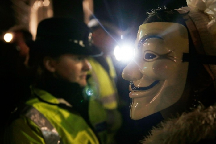 Membri şi suporteri ai grupului de hackeri Anonymous, împreună cu poliţia în faţa Parlamentului britanic, 5 noiembrie 2012, Londra