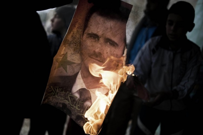 Un membru al Armatei Siriene de Eliberare ţine un portret arzând al preşedintelui Bashar al-Assad în Al-Qsair, arhivă